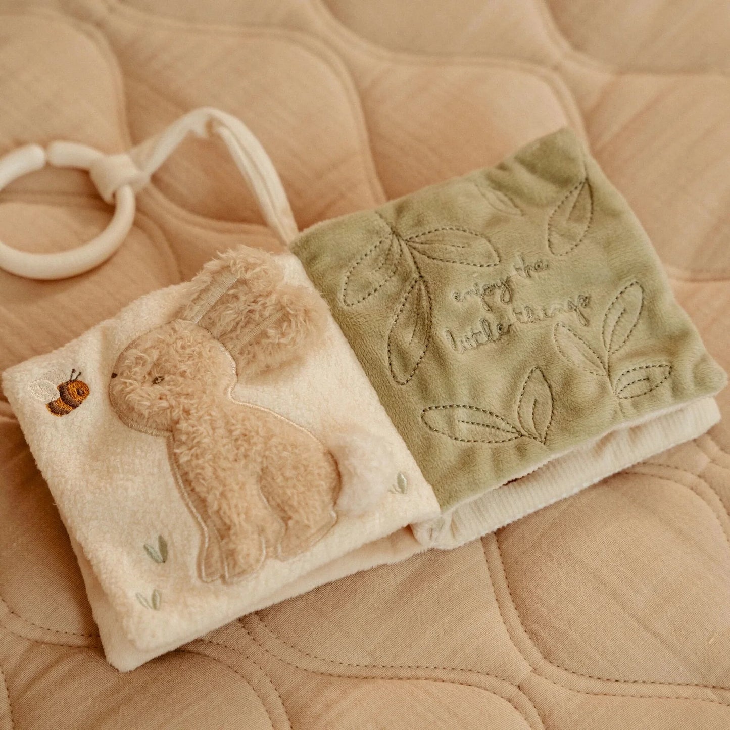 Vista do interior do livrinho, com páginas que incluem diferentes tecidos, sons e imagens suaves. Adaptado para mãos pequenas.