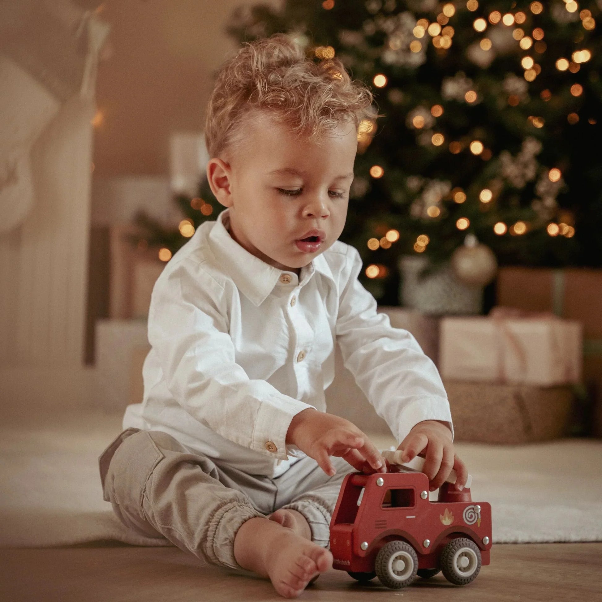 Criança pequena a brincar com Camião de Bombeiros em Madeira Vermelho