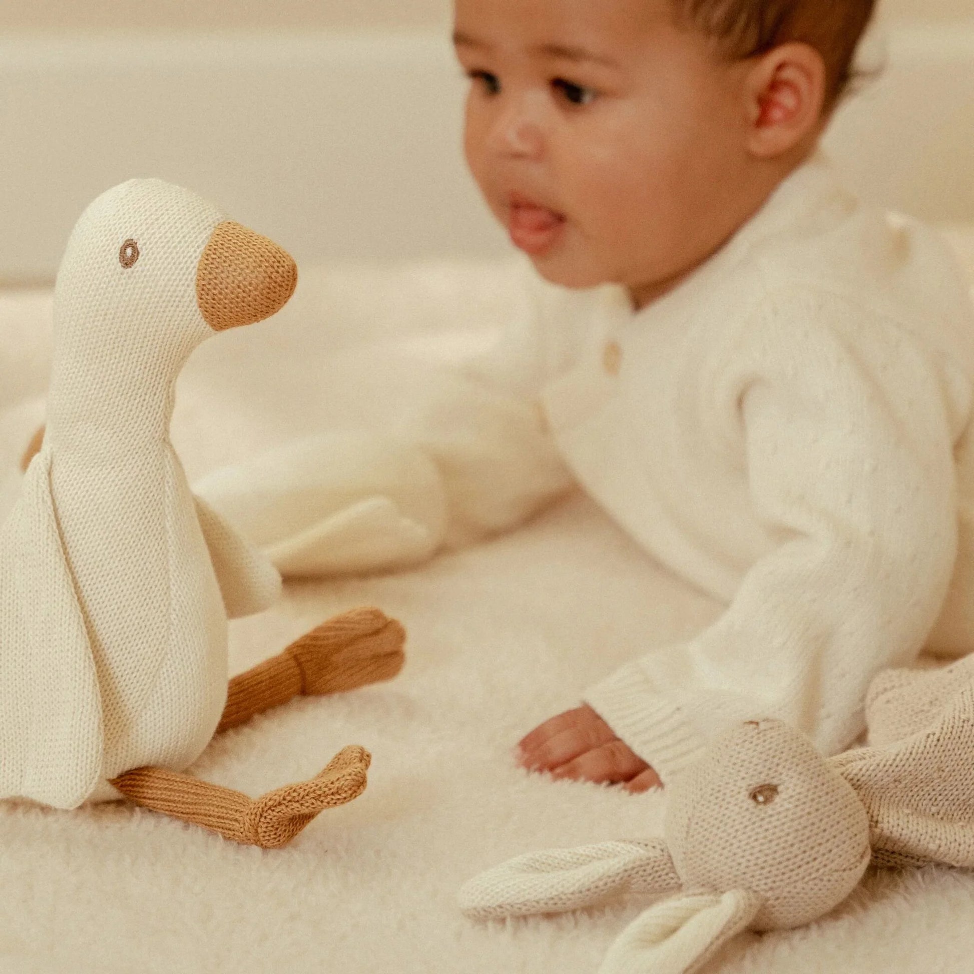 Bebé a observar os acessórios que pertencem ao Conjunto de Nascimento Newborn Naturals Bege