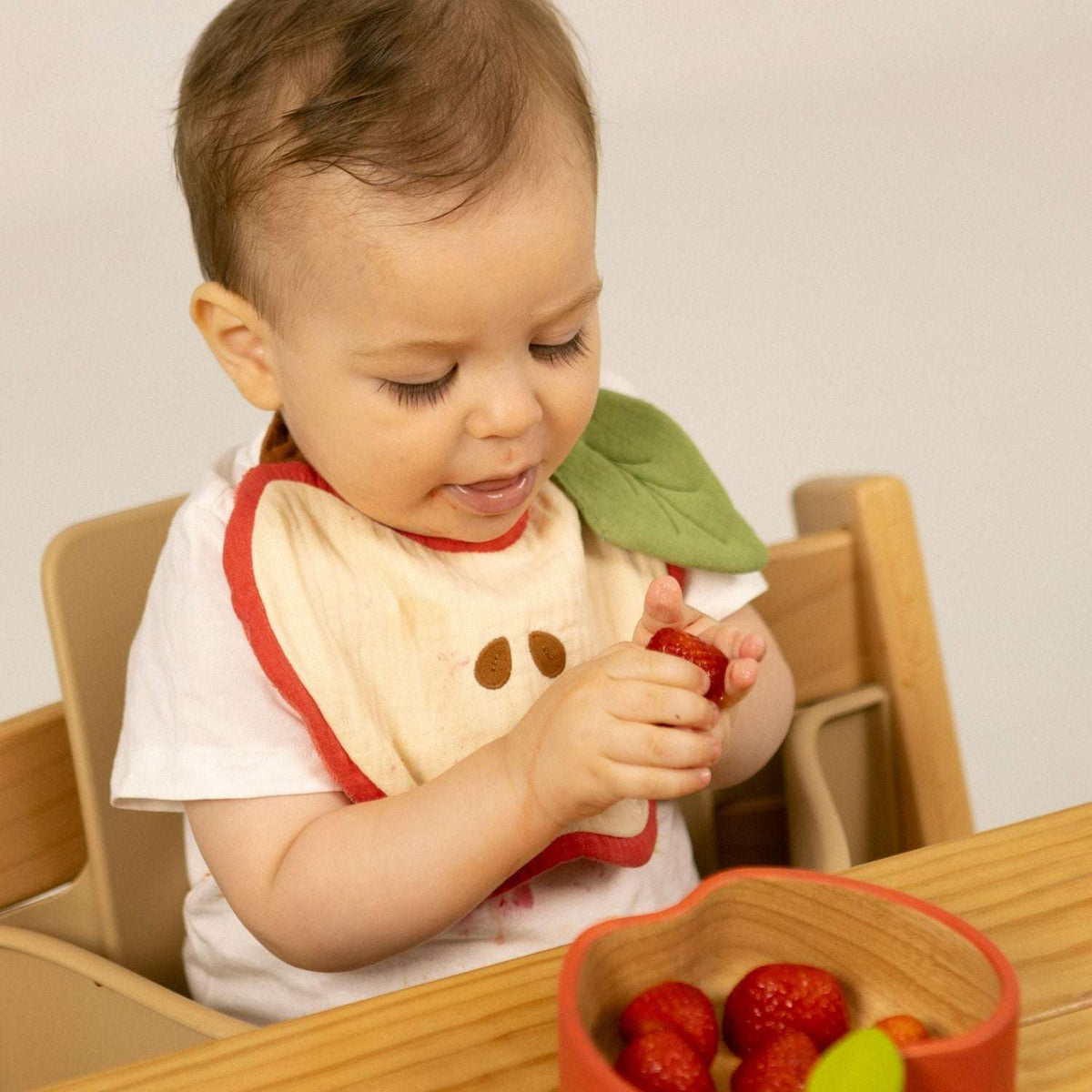Bebé a comer fruta com o babete Pepa a Maçã da Oli & Carol | oli-carol-babete-maca-lollakids